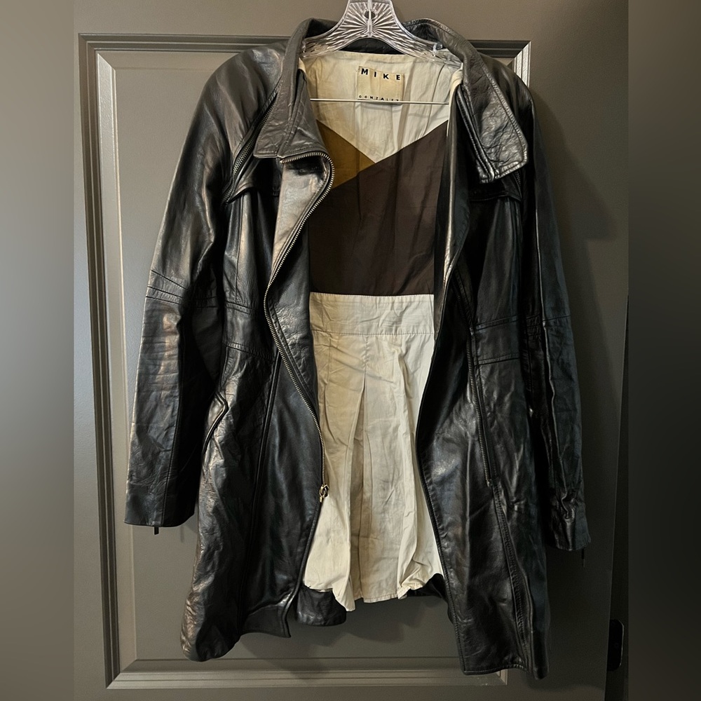 Black leather Mike Gonzalez trench coat. Zipper cuff detail with pockets.